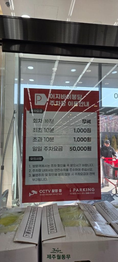 Sign on the glass door detailing parking fees at Easy Buy Supermarket Bongdam.