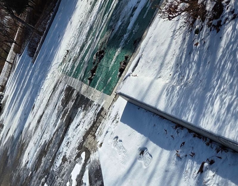 주차장 근처 보행로에 눈이 쌓여 있고 그위로 발자국들이 보인다.