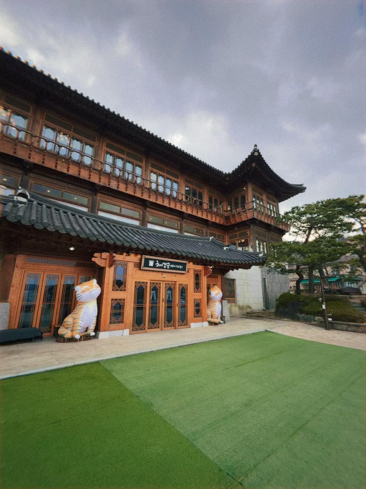 木製の柱、瓦屋根、そして提灯が飾られた韓国の伝統的な建物のエントランスの全景。