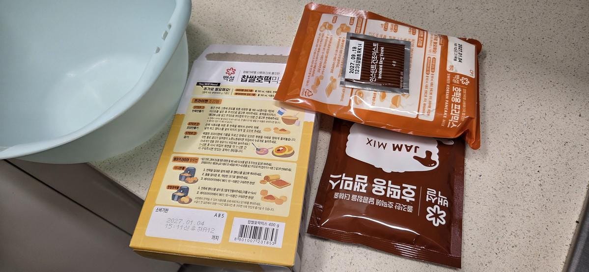 Three sealed plastic packets containing yeast, dough powder, and sugar filling mix laid out.