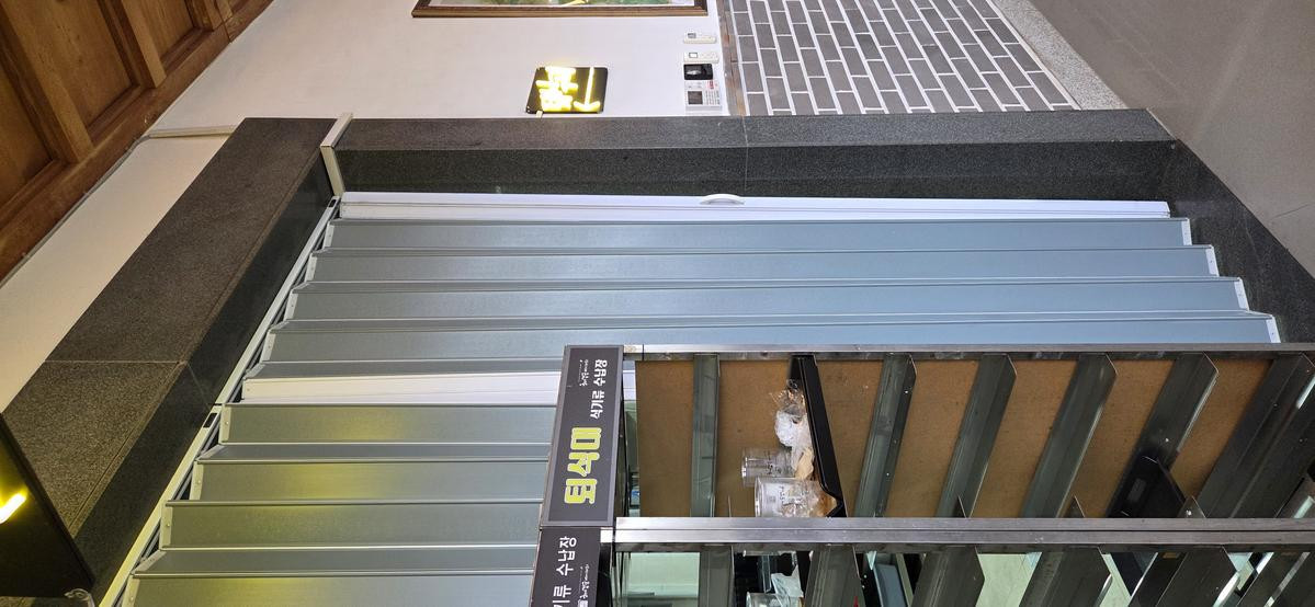 ダークウッドのキャビネット、シンク、電子レンジ、そして積み重ねられたトレイがあるセルフサービスの返却コーナー。