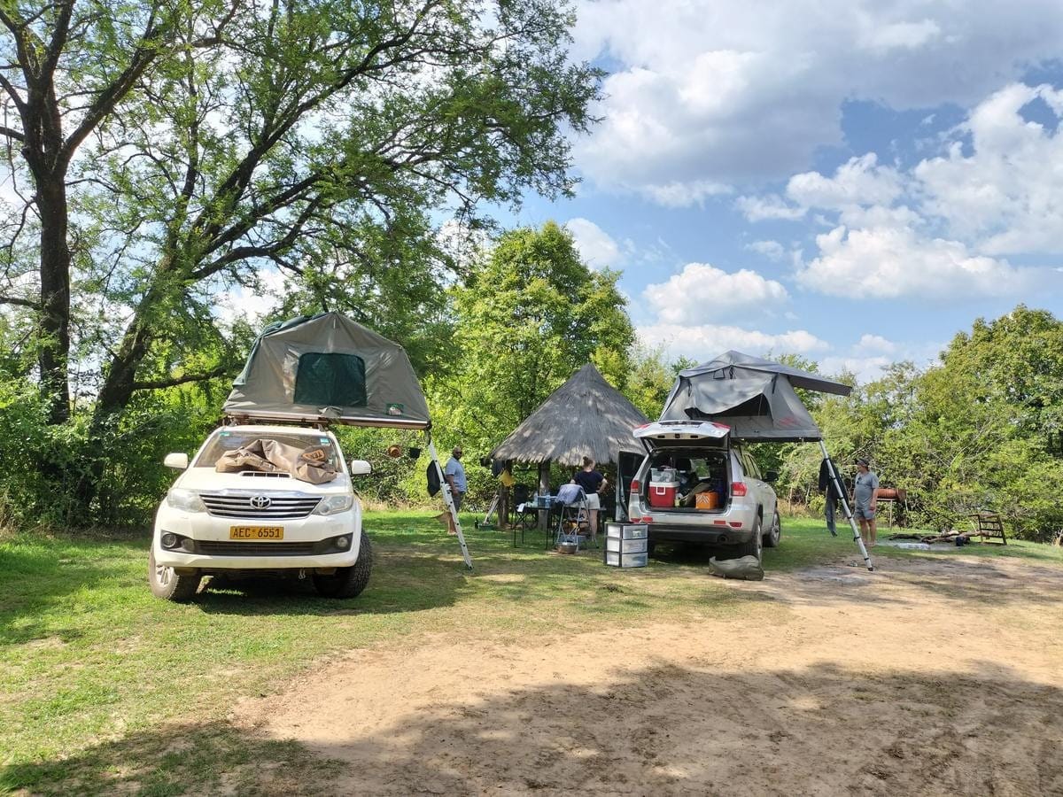 Two adults and a child sitting on the roof rack of a white off-road vehicle.