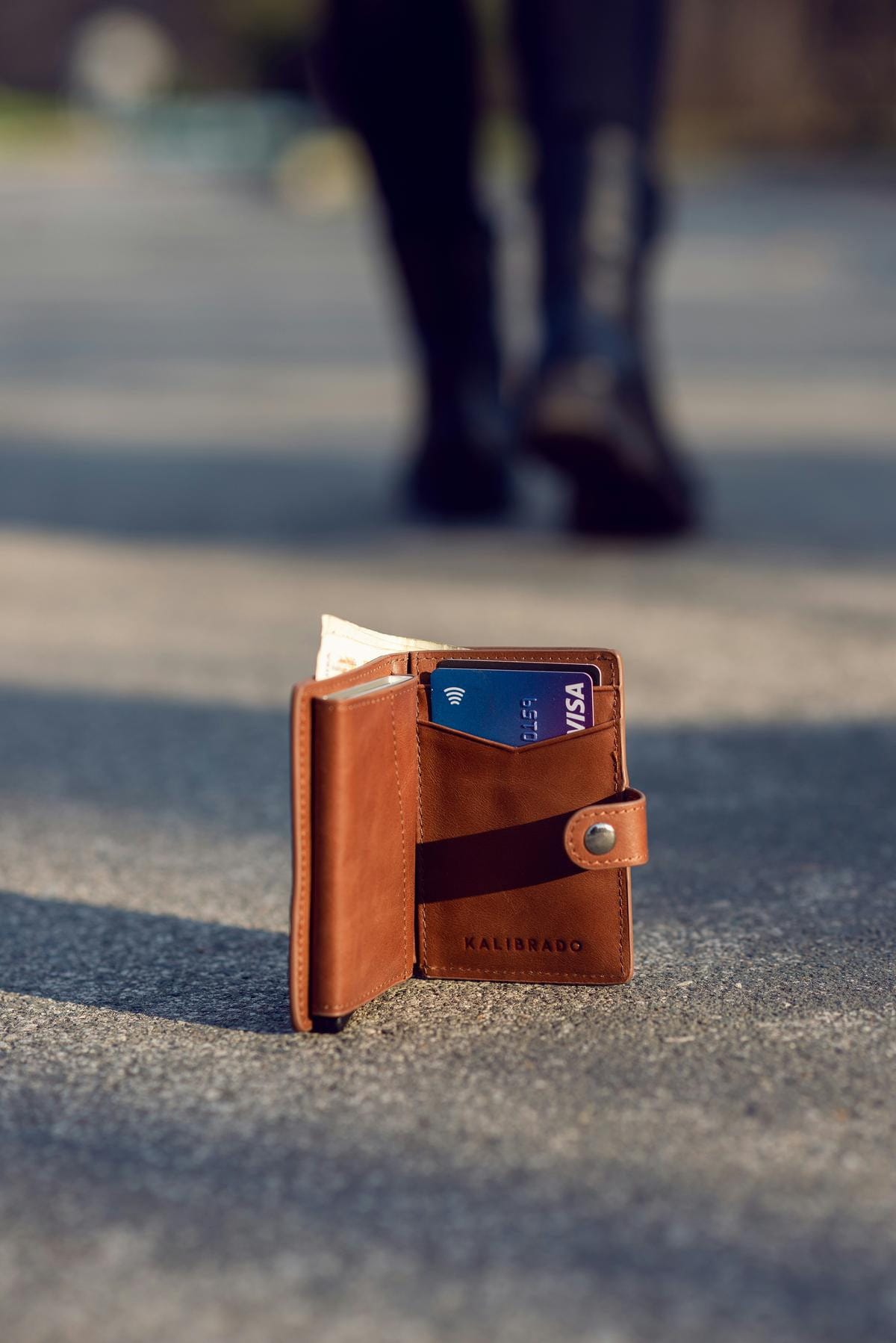 A brown leather wallet resting unattended on a wooden table with a blurred background.