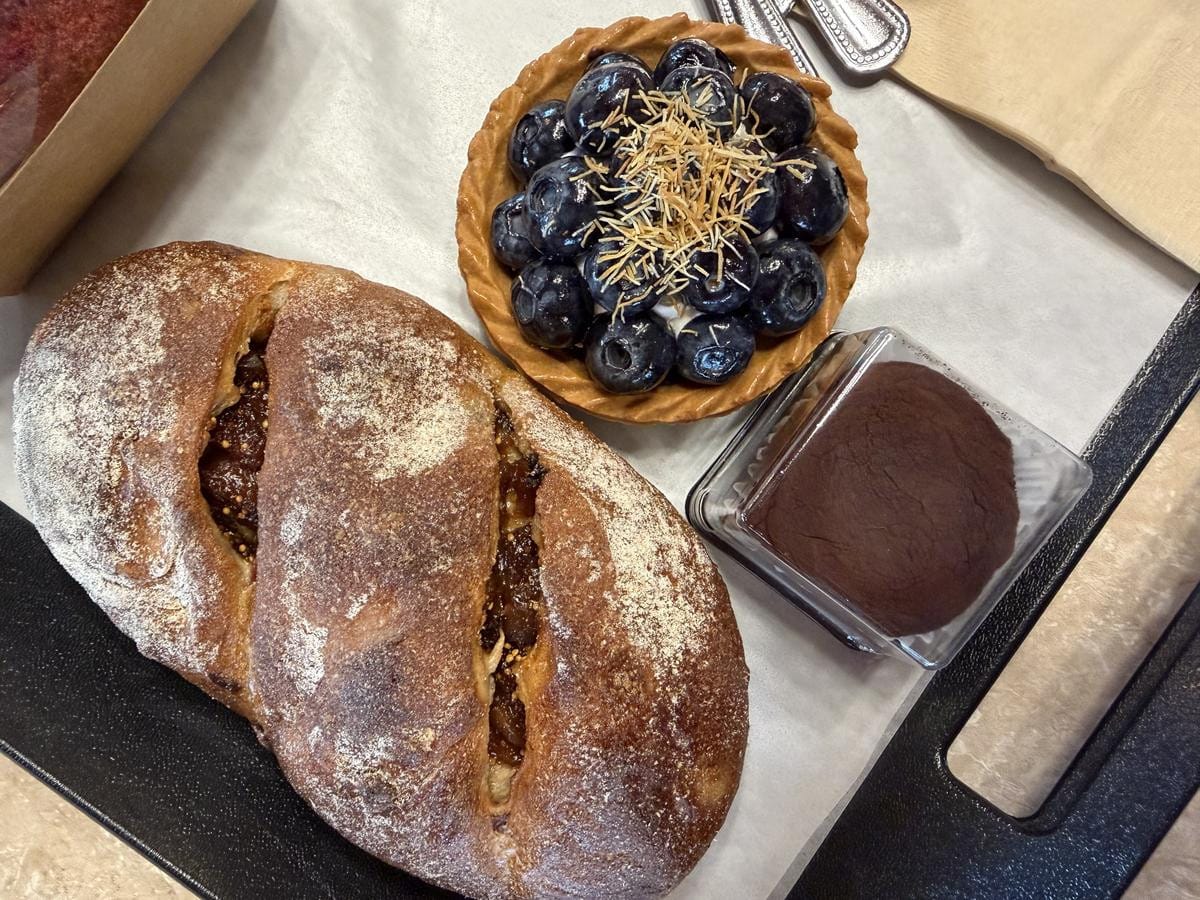 작고 둥근 페이스트리 위에 신선하게 자른 무화과와 통 블루베리가 장식된 베이커리 진열대