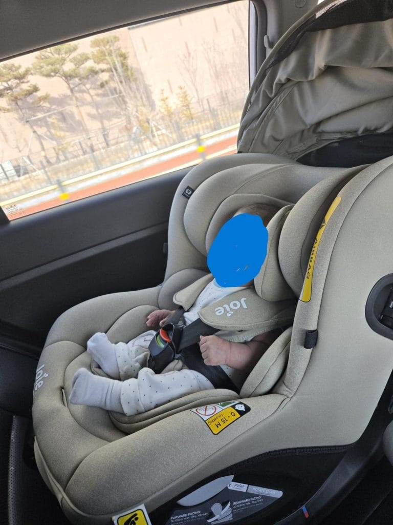 A newborn baby securely strapped into a rear-facing infant car seat inside a vehicle.