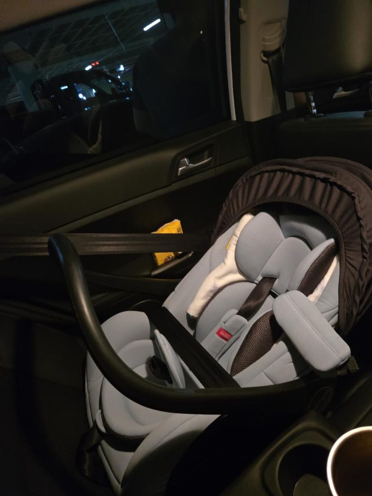 A rear-facing infant car seat installed securely in the back seat of a vehicle.