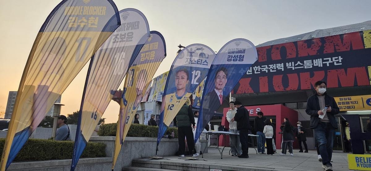Large banners featuring portraits of a coach and volleyball players hang from a ceiling.