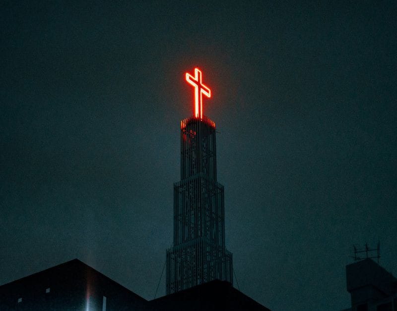 Red neon cross on a church building at night