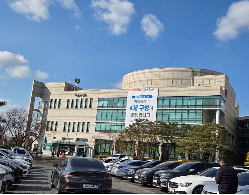The large, modern exterior of the Hwaseong City Ward Office on a sunny day.