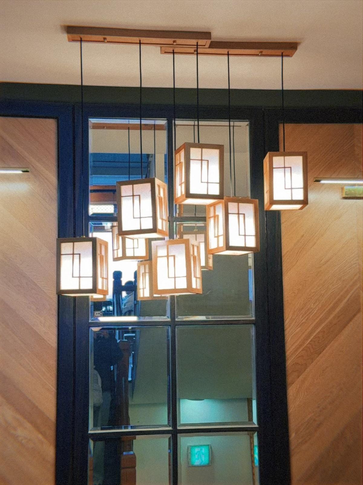 거대한 전통 한옥 내부 천장의 서까래와 그 아래 은은하게 빛나는 직사각형 조명들