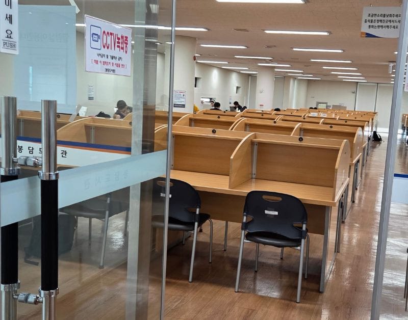 Rows of individual wooden study desks with dividers inside the library's quiet reading room.