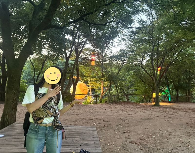 A Japanese student posing with a glowing yellow moon installation at the Yongin Folk Village.
