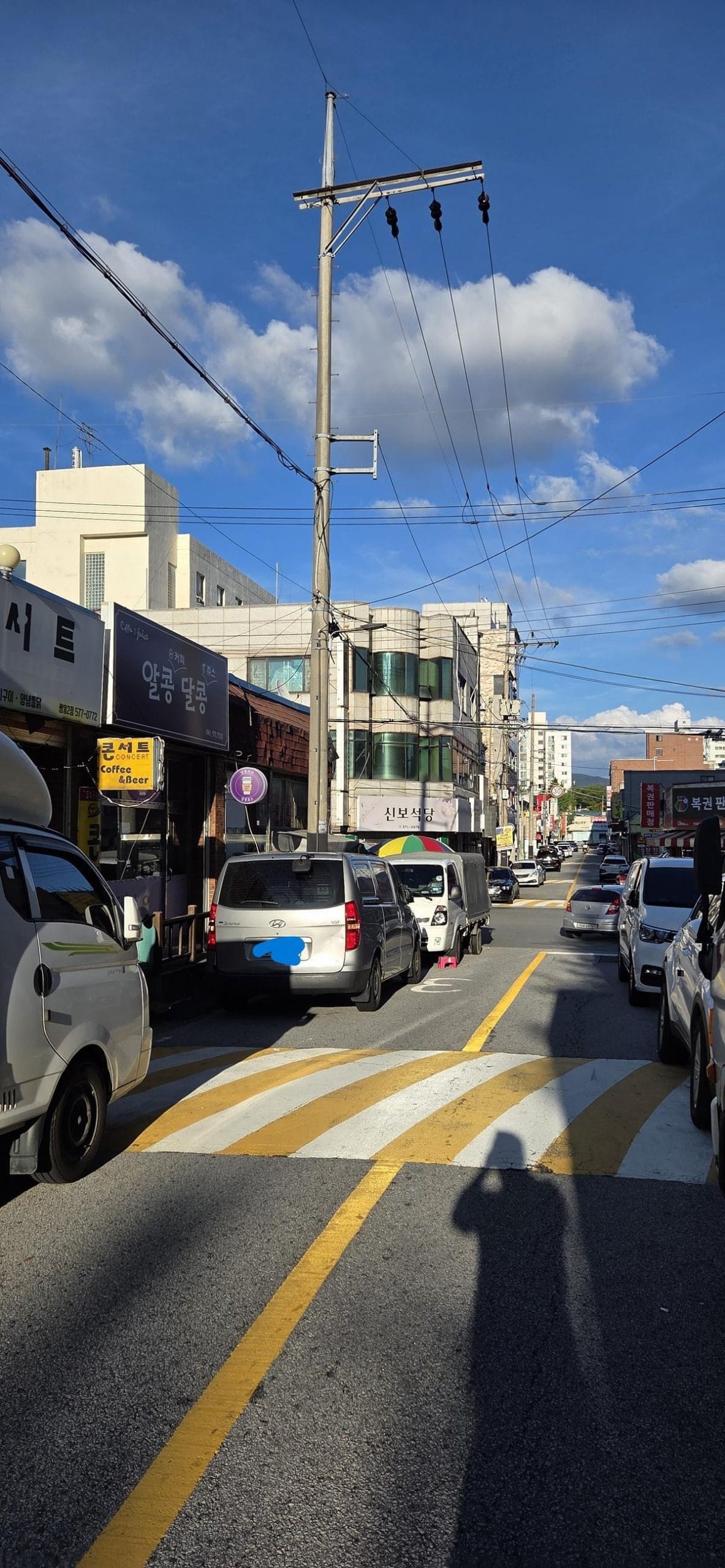 Several cars parked tightly together on a paved surface directly in front of a storefront.