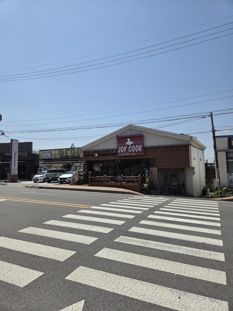 塗装された白い横断歩道と交通信号機を備えた、幅の広い多車線のアスファルト道路