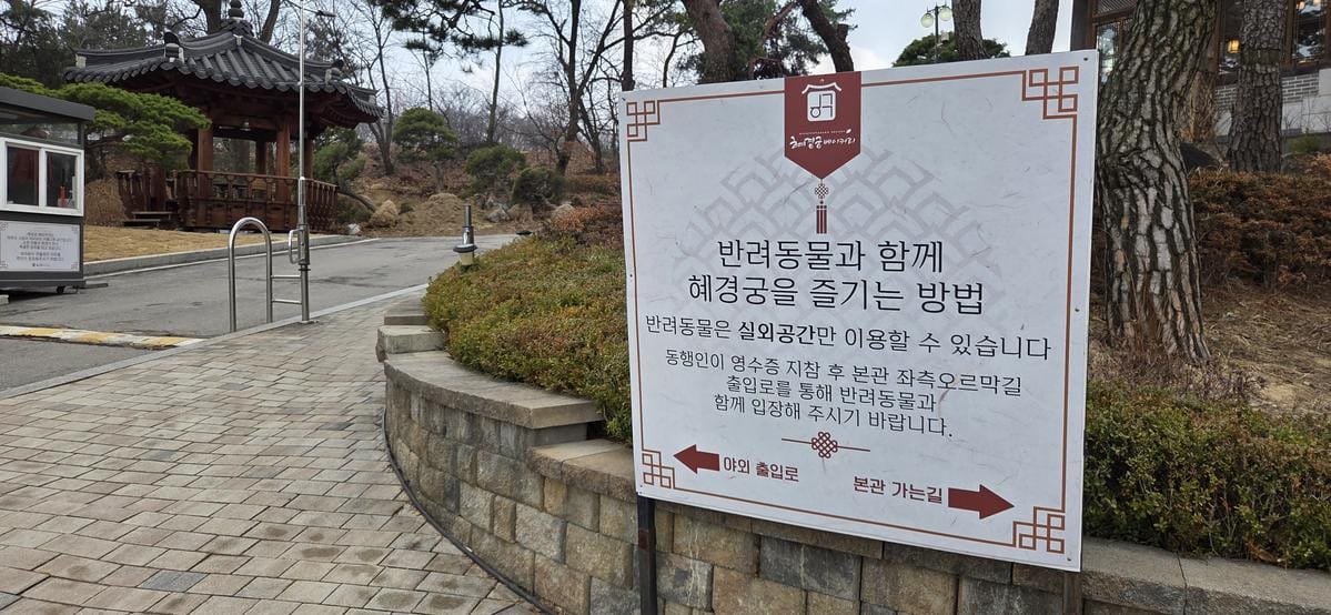 돌담과 잎이 진 나무들, 전통 나무 문으로 둘러싸인 야외 포장 산책로