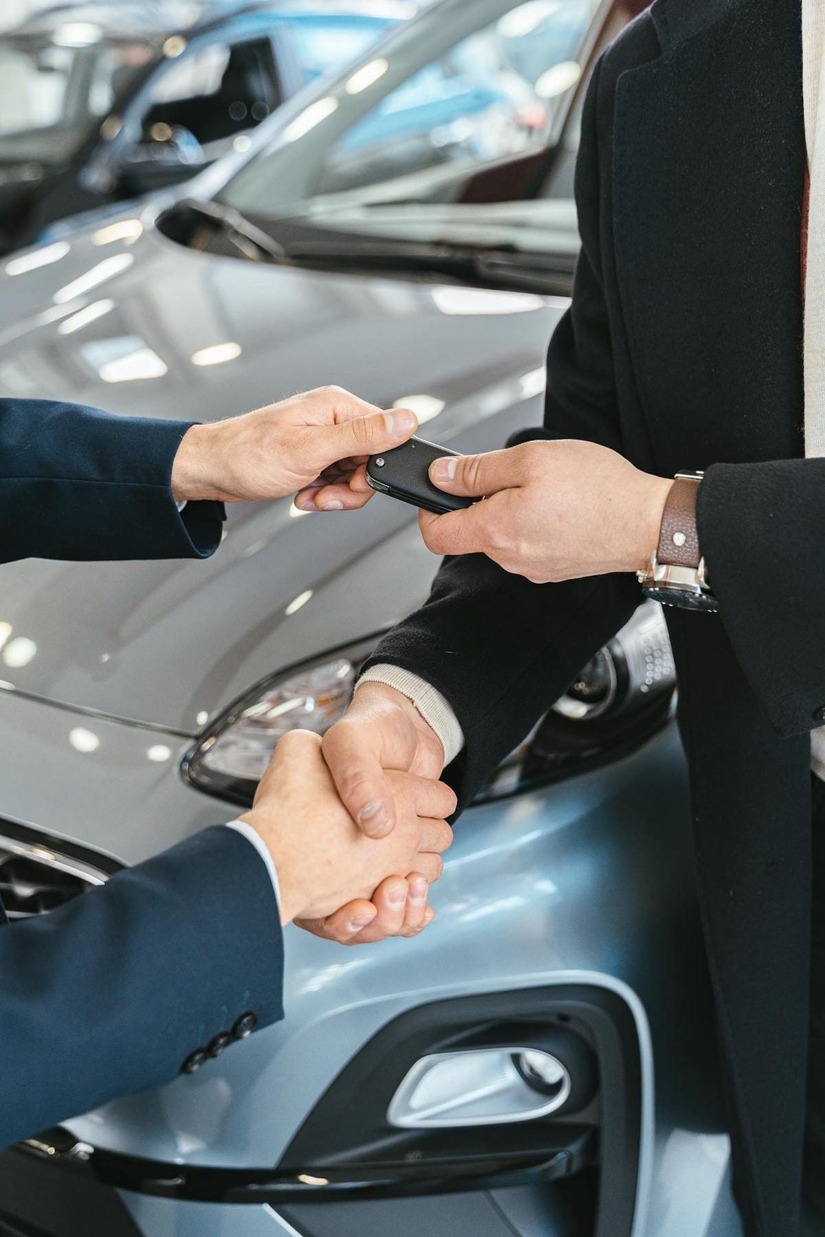Close-up of one person's hand passing a black car key fob to another person's hand.