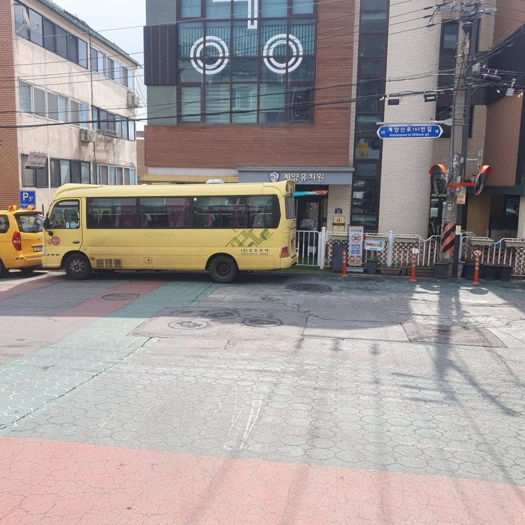 A yellow school bus on a city street near a 30km/h speed limit road sign.