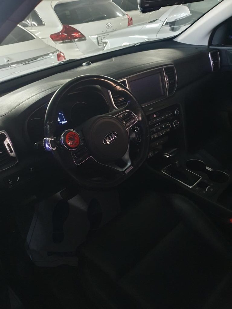 Interior view of a car showing the steering wheel, dashboard, center console, and front seats.