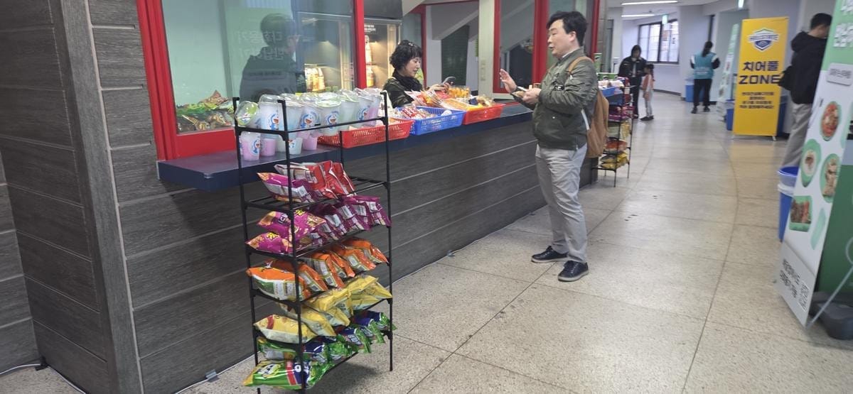 A small convenience stand sells snacks and drinks inside a stadium concourse.