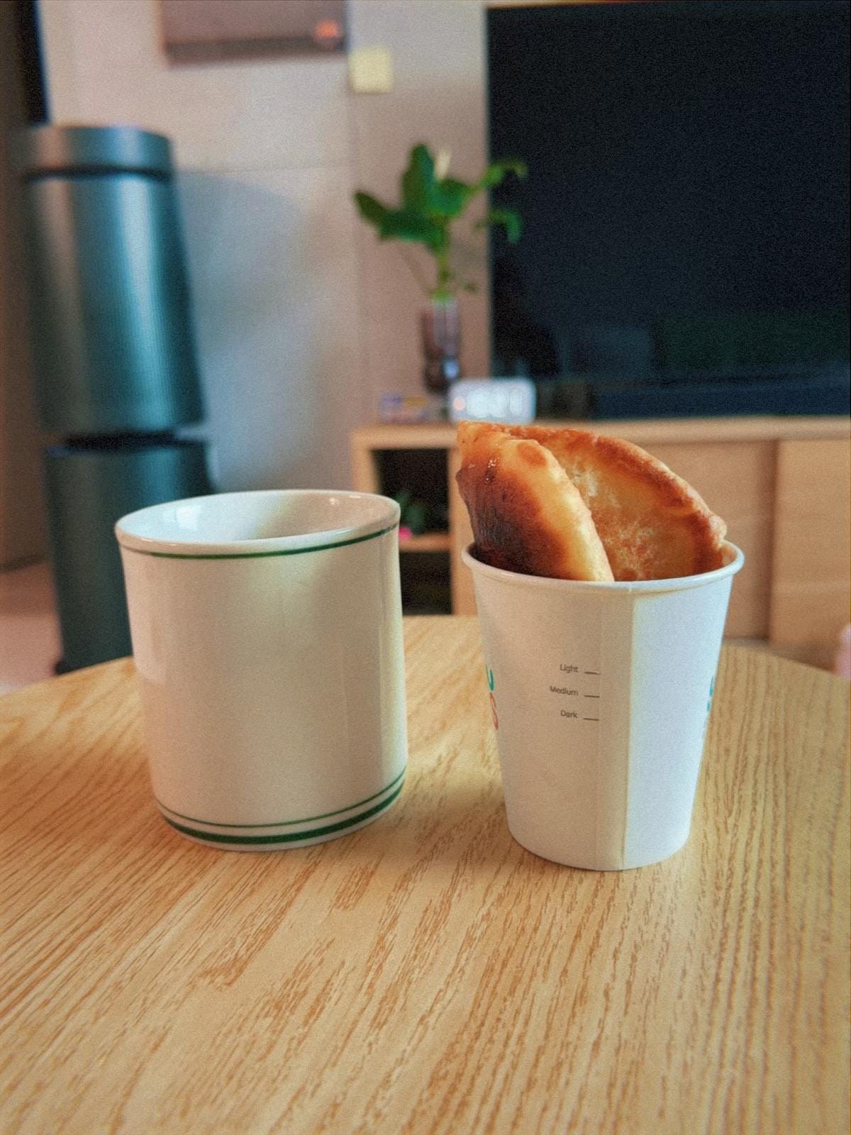 접시 위에 담긴 노릇노릇하게 구워진 호떡과 옆에 놓인 블랙커피가 담긴 머그잔.