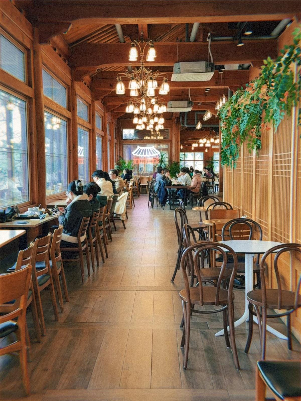 曲線状の伝統的な瓦屋根の下にある屋外の木製通路から、遠くの風景と澄み切った空を見渡す景色。