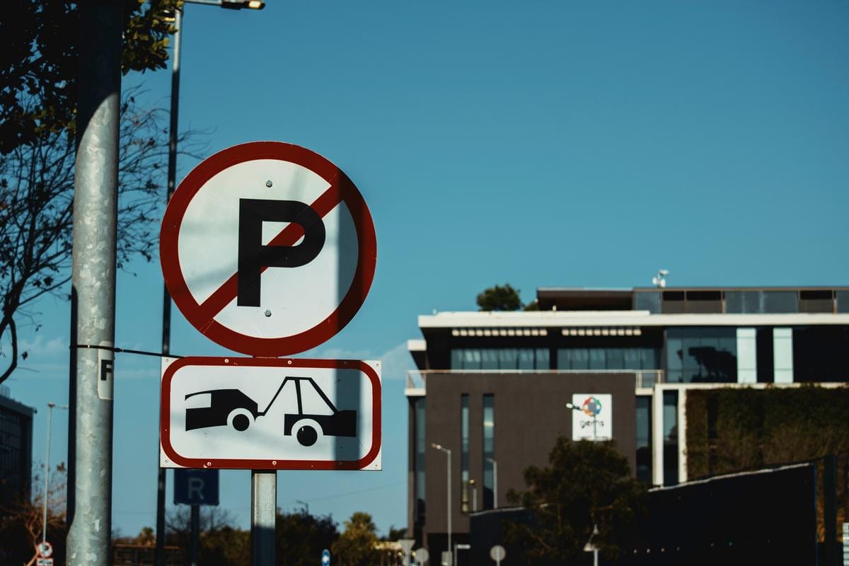 도시 도로에서 소형 승용차를 들어 올려 운반하고 있는 대형 견인차.