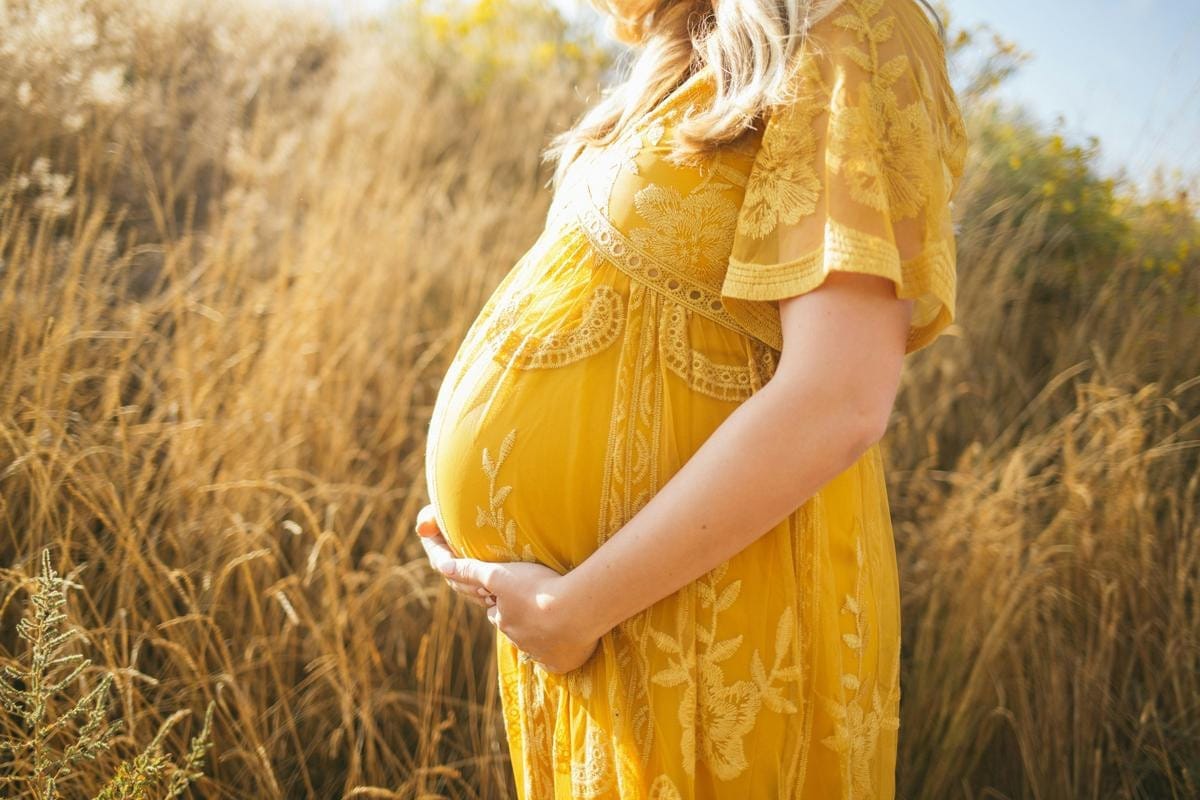 A pregnant woman places her hands on her stomach.