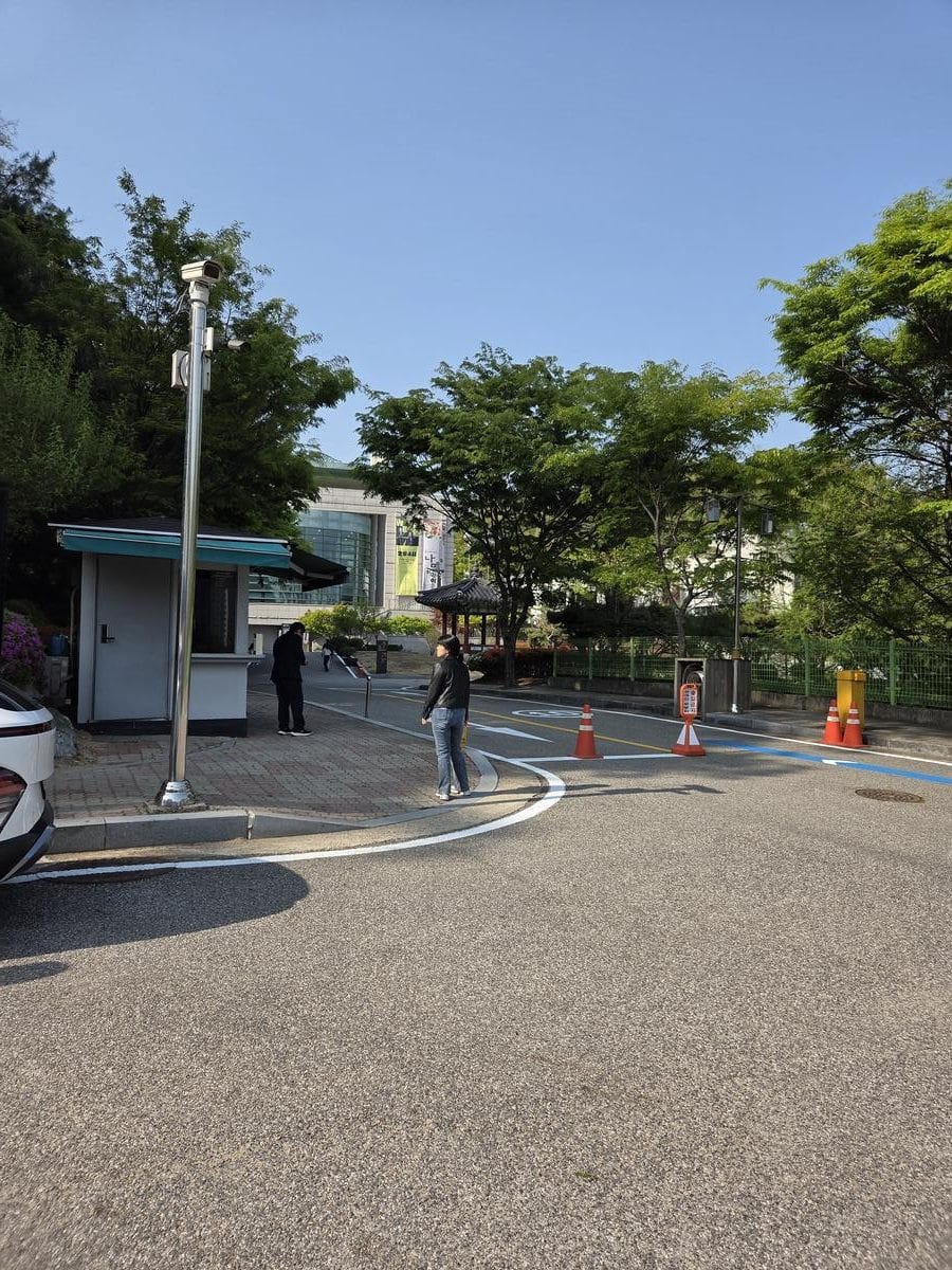 駐車場から舗装されたエリア越しに伝統的な建物の入り口を見た様子。