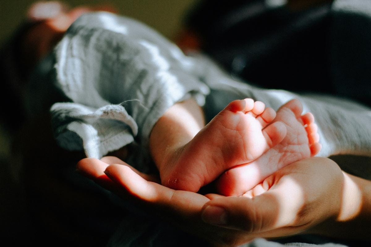 A baby eats pureed food from a small spoon.