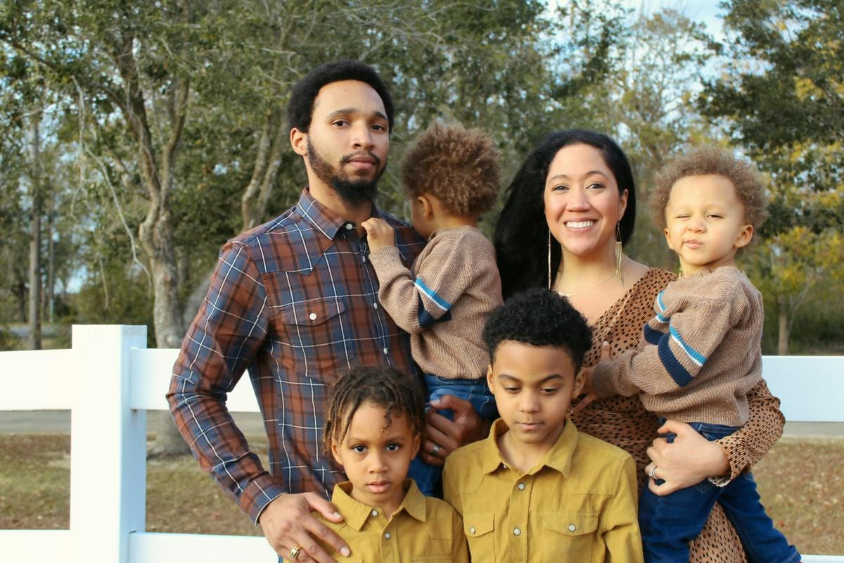 A man, woman, and young child stand close together outdoors.