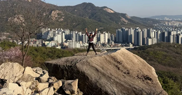 Expat hiker sitting on a scenic rock formation while hiking Seoul Trail Course 2.