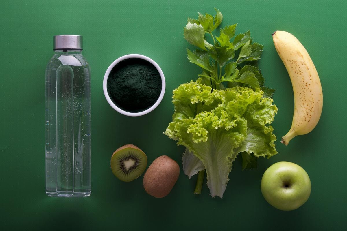 A variety of fresh vegetables, fruits, and healthy foods are arranged on a flat surface.