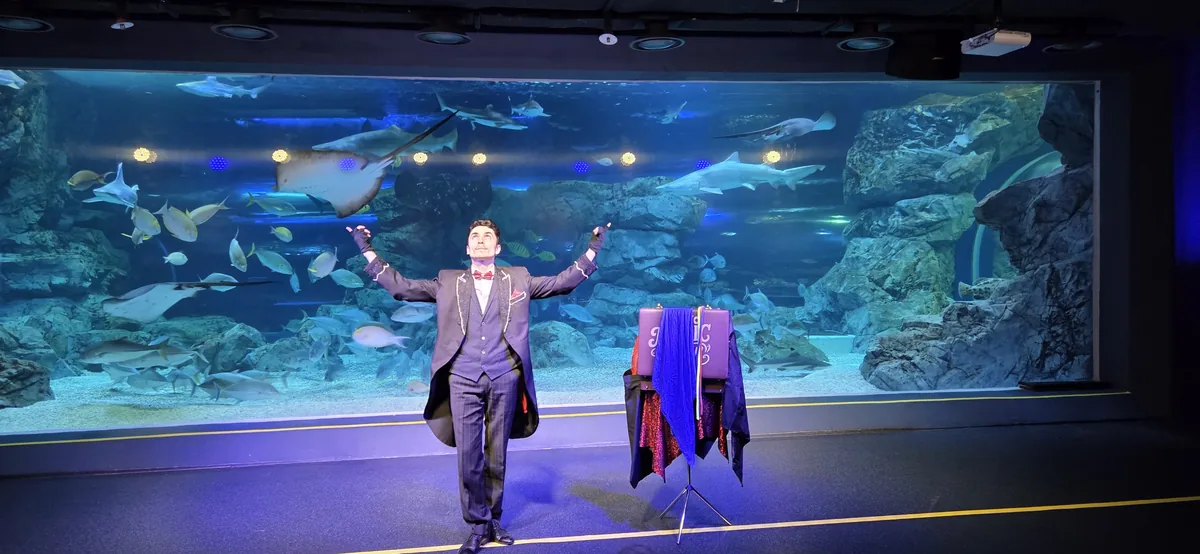 A magician performs tricks on stage, part of Gwanggyo Aquaplanet interactive exhibits.