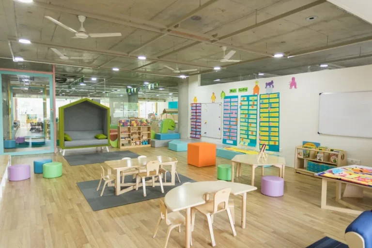 A brightly lit, empty childcare room with colourful play mats and toys, ready for children.
