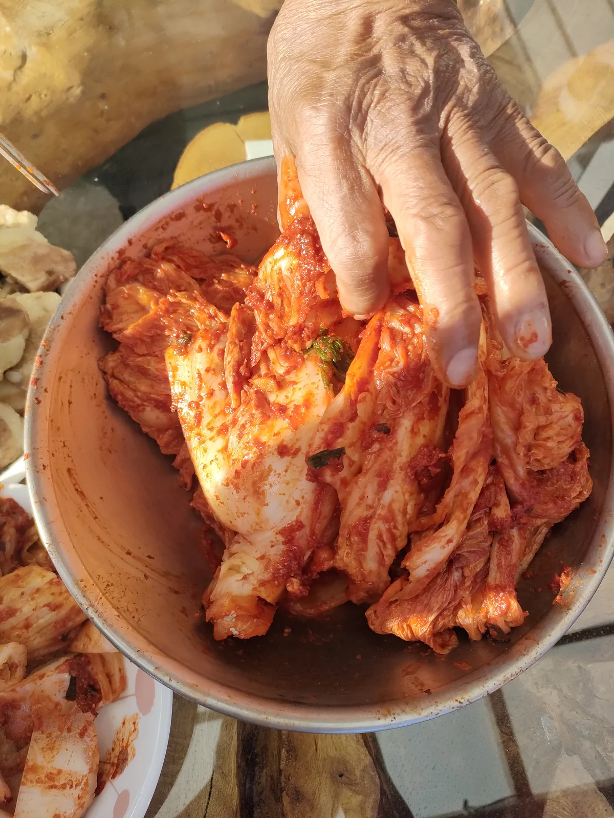 A hand placing freshly made spicy kimchi into a bowl during a kimjang kimchi family tradition expat korea.