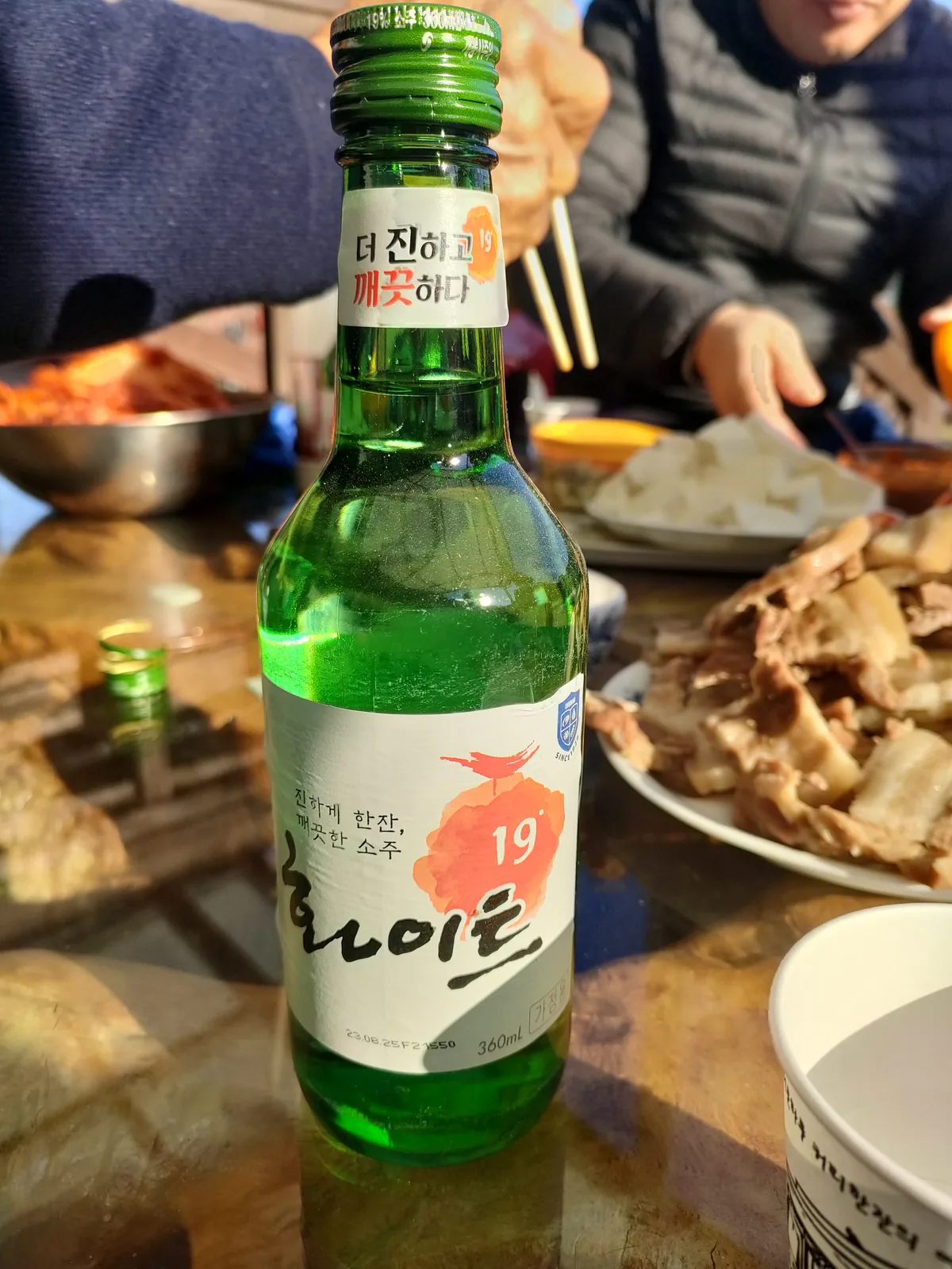 A green bottle of Hite soju served with boiled pork and fresh kimjang kimchi family tradition expat korea.