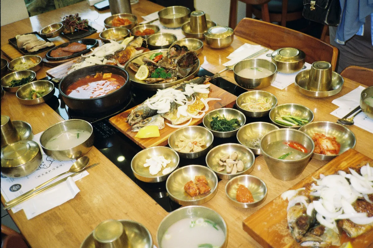 A traditional Korean restaurant table completely covered in dozens of small banchan dishes.