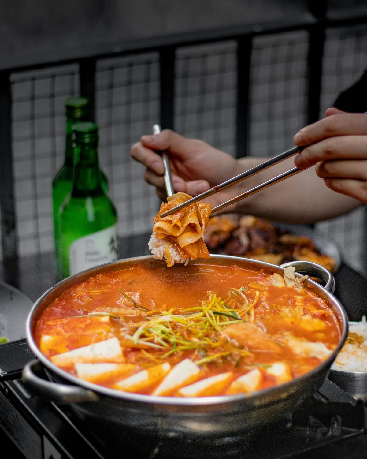 A bubbling pot of jjigae centered on a restaurant table, a classic element of traditional korean restaurant etiquette.