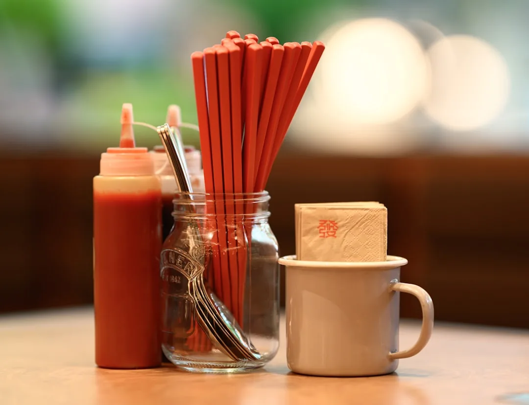 Korean metal chopsticks and a spoon resting in a glass jar at a restaurant table.