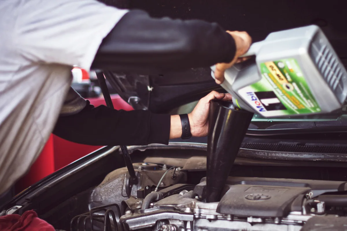 A mechanic inspecting a car tire tread during professional car maintenance in Korea.