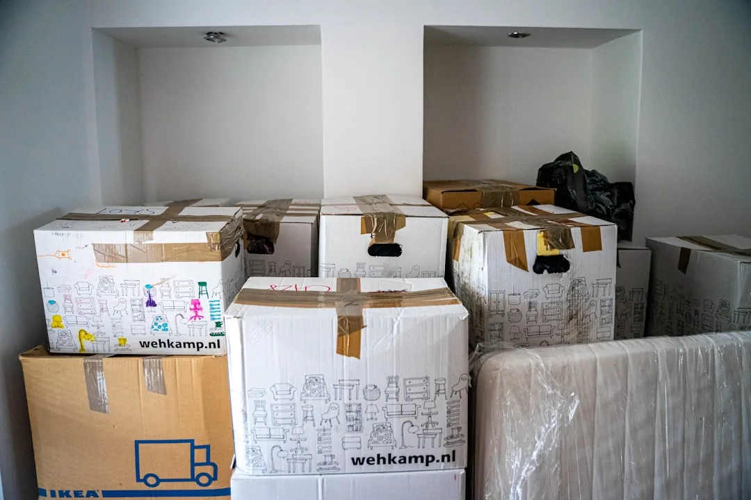 Moving boxes stacked in an empty room with white shelving units.