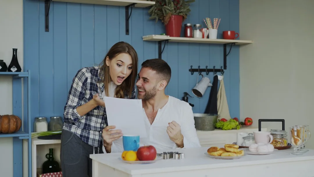 Couple in modern kitchen looking at tablet together, smiling.