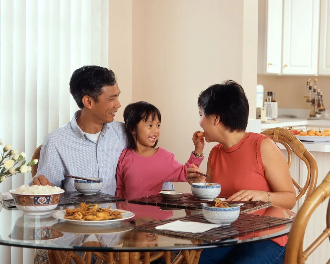 A diverse family happily eats a homemade, balanced meal together.
