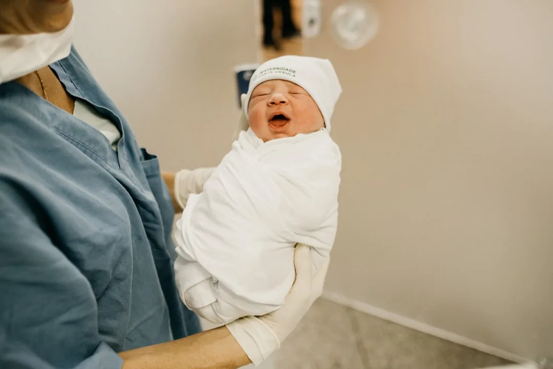 A mother tenderly holding her baby close, both looking at each other.