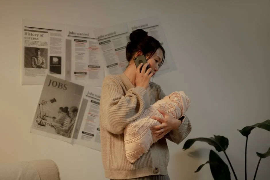 Woman holding a baby while talking on her phone indoors.