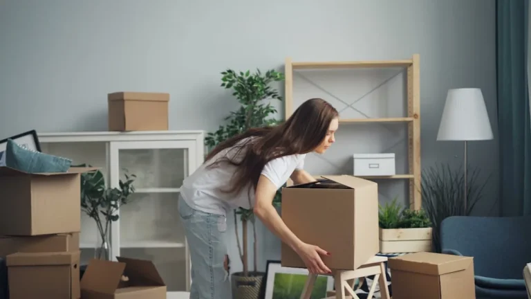 現代的なアパートメント内で段ボール箱に荷物を詰める女性