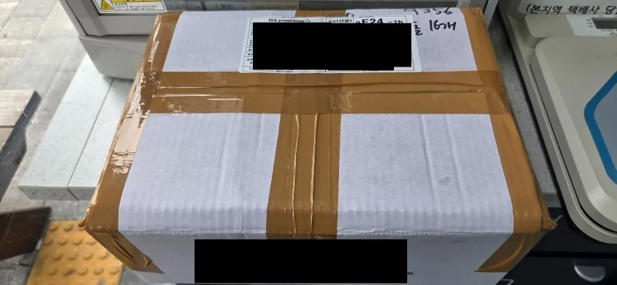 Cardboard parcel wrapped with brown tape and white padding material sits on a surface.