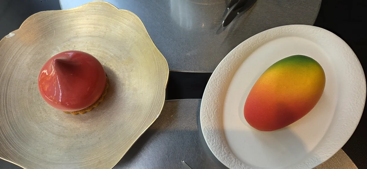 Two plated desserts with glossy red and gradient toppings on white ceramic plates.