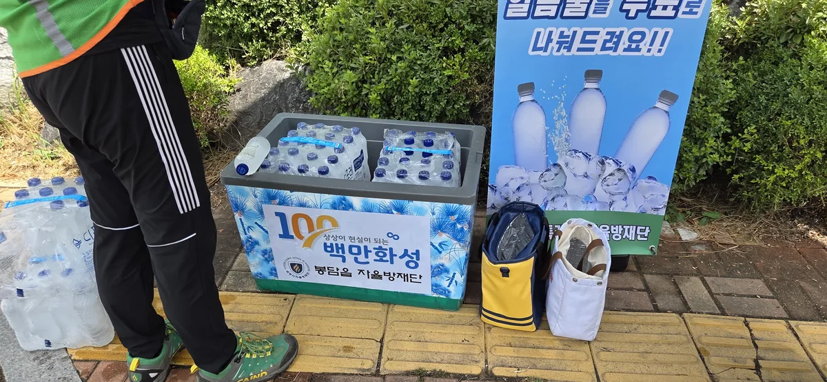 Street stand displaying packaged bottled water and promotional signage in Korean.