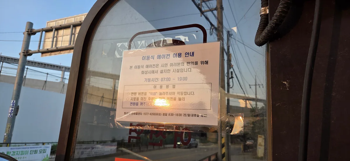 Korean notice listing the daytime operating hours of a bus stop cooling unit